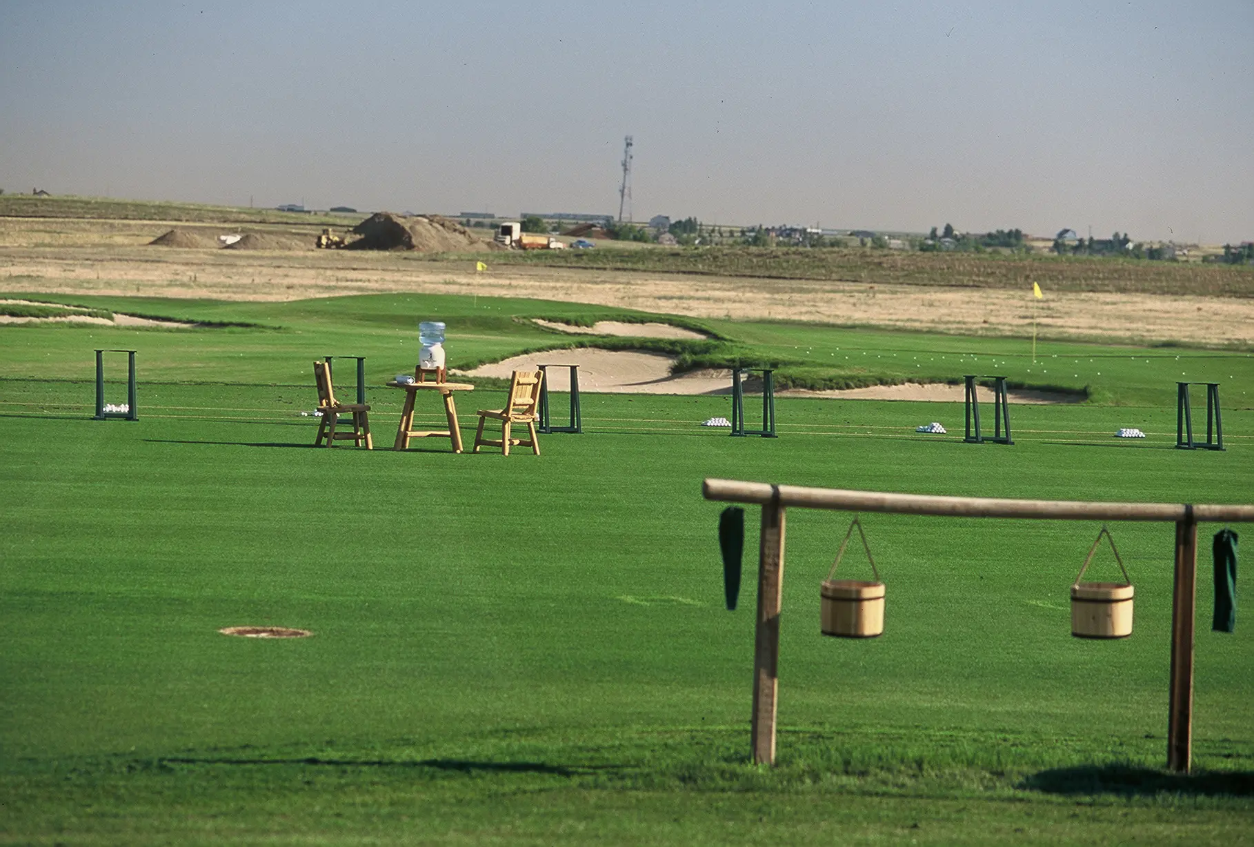 A golf course with tables and chairs on the grass.