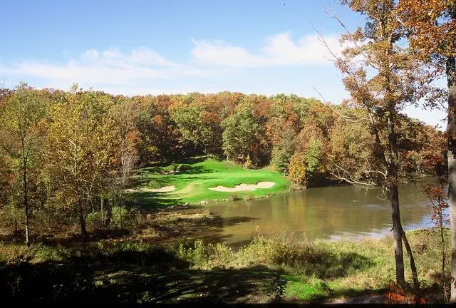 A golf course with trees and water in the background.