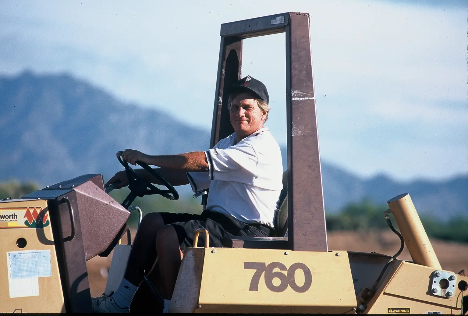 A man driving a large yellow truck.