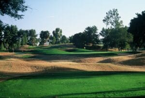 A golf course with trees and green grass.