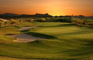 A golf course with the sun setting in the background.