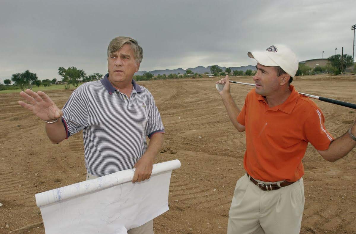 Two men standing in a field with one holding something.