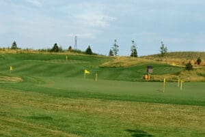 A golf course with green and yellow flags on the side.